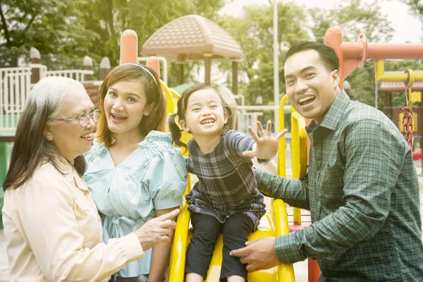 Menina brincando com sua família no playground — Fotografia de Stock