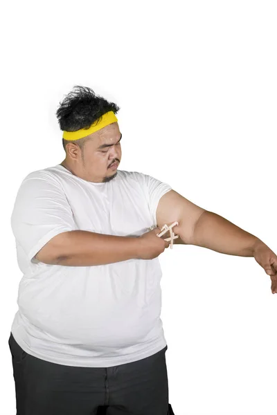 Young man measures fat layer of his arm on studio — Stock Photo, Image