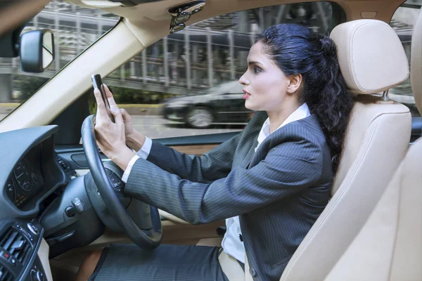 Mujer de negocios conduciendo el coche mientras usa el teléfono celular — Foto de Stock