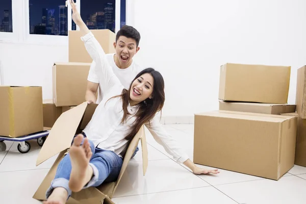 Cheerful couple with a cardboard in new apartment — Stock Photo, Image