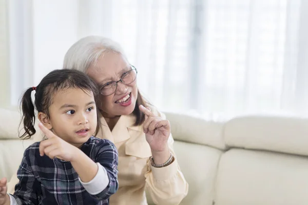 Vrolijke oude vrouw kijkt TV met haar kleinkind — Stockfoto