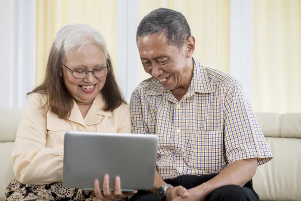 Heureux couple âgé utilisant un ordinateur portable à la maison — Photo
