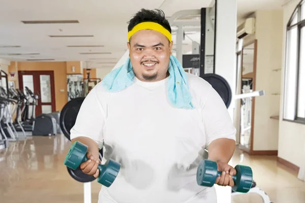 Homem gordo feliz exercita seu bíceps com halteres — Fotografia de Stock