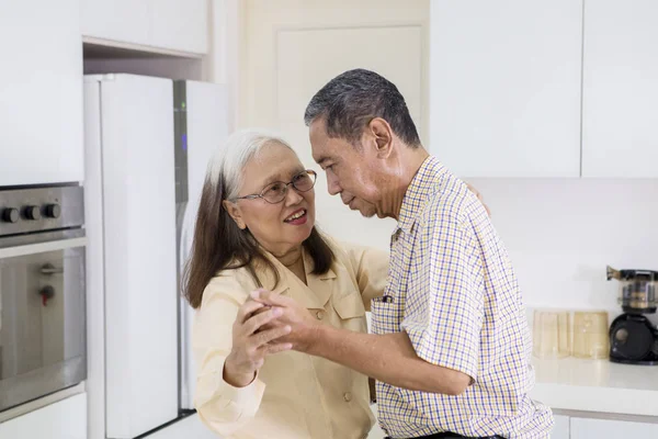 Heureux vieux couple dansant ensemble dans la cuisine — Photo