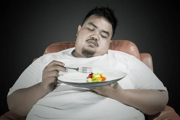 Homem preguiçoso com sobrepeso come comida saudável — Fotografia de Stock