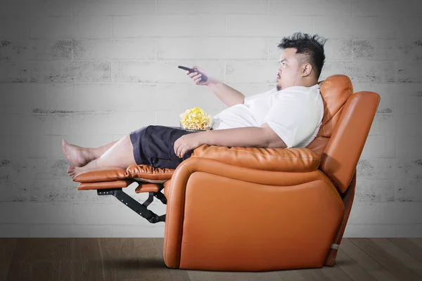 Obèse homme mange du pop-corn pendant regarder la télévision à la maison — Photo