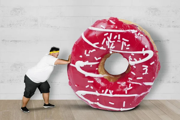 Obese man pushing a big donut
