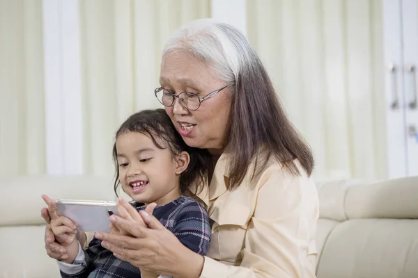 Vieille femme utilisant un téléphone avec son petit-enfant — Photo