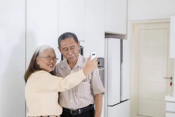 Coppia anziana scatta una foto insieme in cucina — Foto Stock