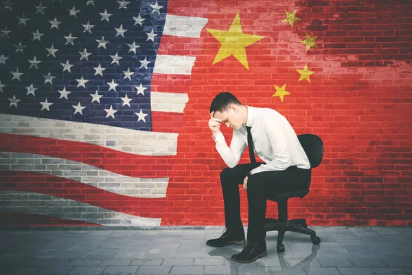 紧张的商人坐在中国和乌萨国旗 — 图库照片