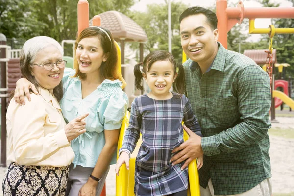 Сім'я трьох поколінь виглядає щасливою на дитячому майданчику — стокове фото