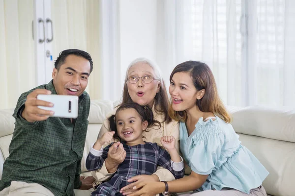 Drie glimlachende generatie familie neemt selfie thuis — Stockfoto