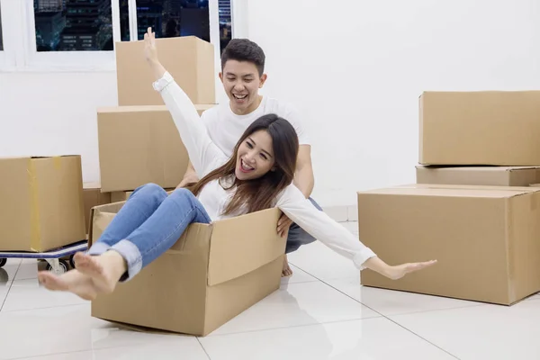Jovem casal asiático montando em uma caixa de papelão — Fotografia de Stock