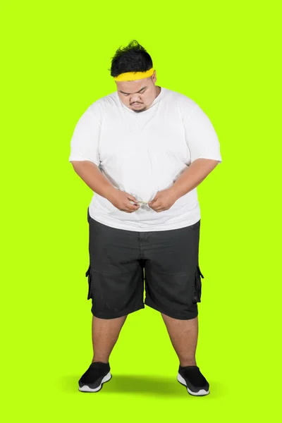 Young fat man measuring his waistline on studio — Stock Photo, Image