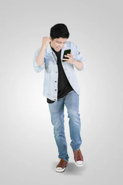 Jonge opgewonden man het lezen van berichten op zijn telefoon — Stockfoto