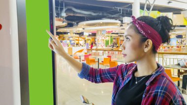 Alışveriş merkezinde self-servis kiosk kullanan Asyalı kadın