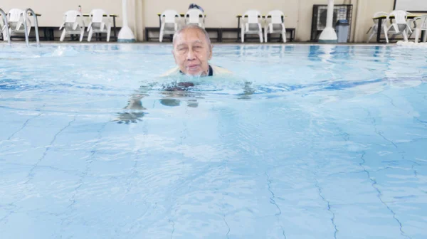 Happy old man swimming in the swim pool