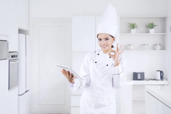 Indian female chef shows OK sign in the kitchen