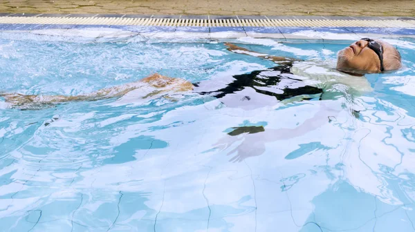 Rilassato uomo anziano galleggia in una piscina — Foto Stock