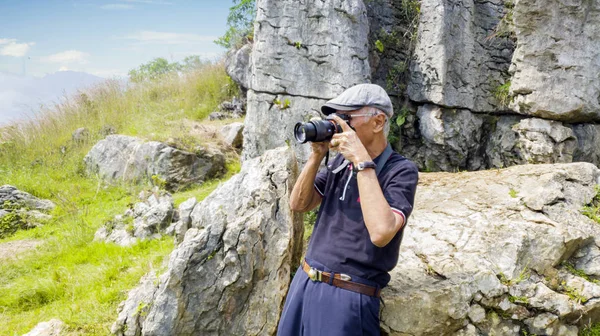 Senior photographer taking a photo near limestones — Stock Photo, Image