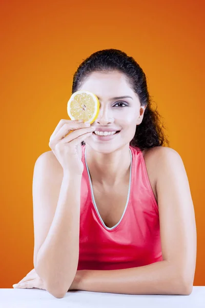 Sorrindo mulher cobrindo seu um olho com laranja — Fotografia de Stock