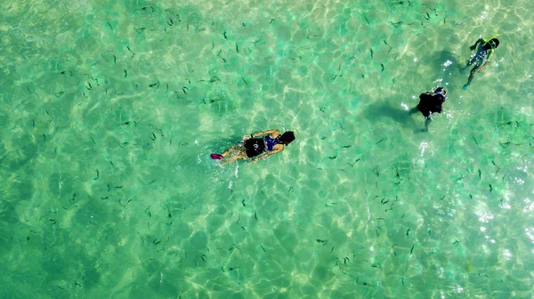 Drie mensen snorkelen in het turquoise water — Stockfoto