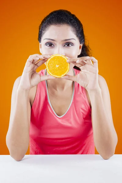 Vrouw die betrekking hebben op haar mond met oranje Fruit — Stockfoto