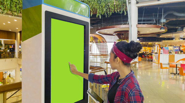 Woman touches a screen of self-ordering kiosk