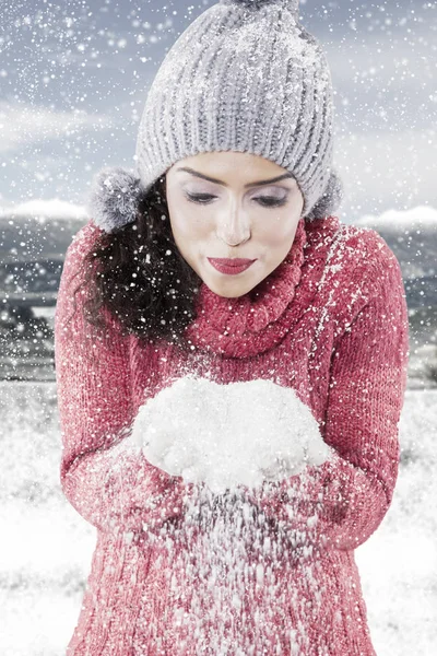 Jonge vrouw waait sneeuw uit haar handen — Stockfoto
