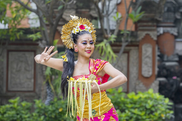 Balinese dancer dances with a bowl of flower petals