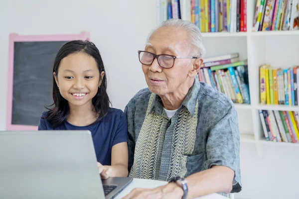 Alter Mann und Enkelin benutzen Laptop in Bibliothek — Stockfoto