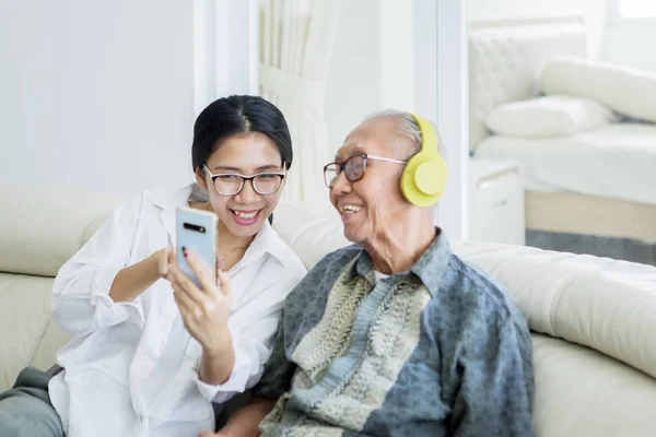 Uomo anziano e figlia godono di musica su smartphone — Foto Stock