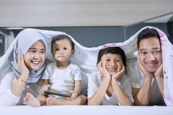Sonriente familia musulmana tendida bajo una manta —  Fotos de Stock
