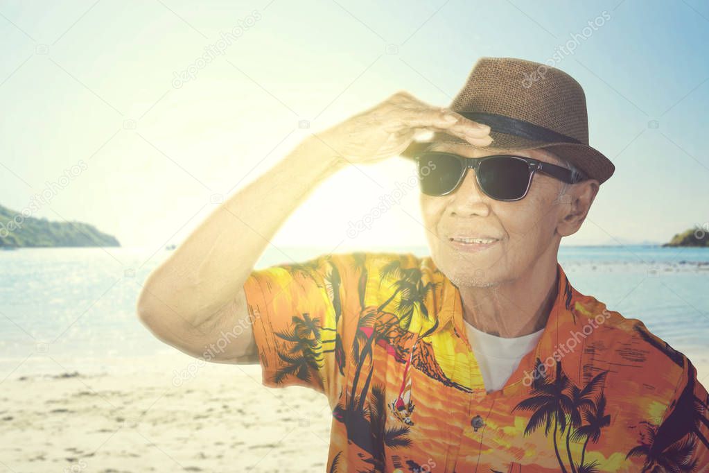 Old man looking far away at sea on the beach