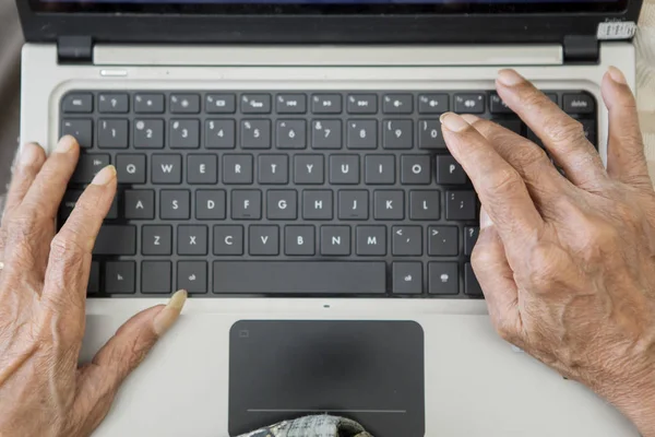 Mani di uomo anziano digitando sul computer portatile — Foto Stock