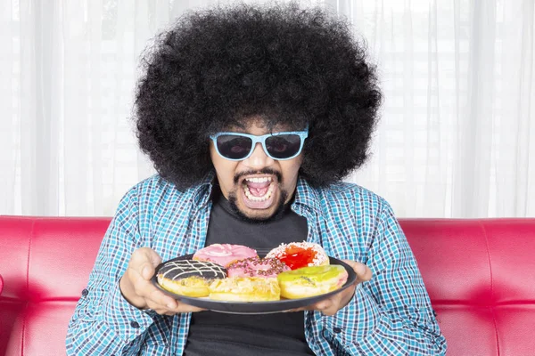 Starving man holding a plate of delicious donuts — Stock Photo, Image