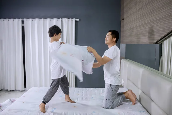 Young man making pillow fight with his son