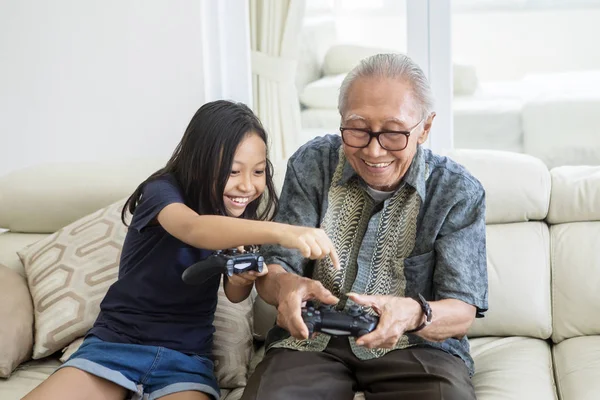 Glückliches Mädchen und ihr Großvater spielen Videospiele — Stockfoto