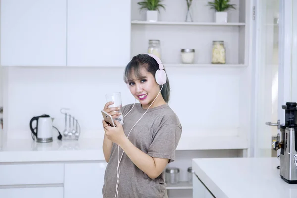 Aziatische vrouw genieten van muziek in de keuken — Stockfoto