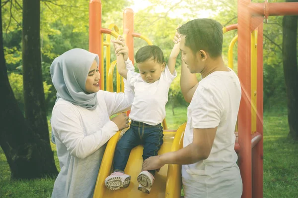 Baby girl plays on a slide with her parents — Stock Photo, Image