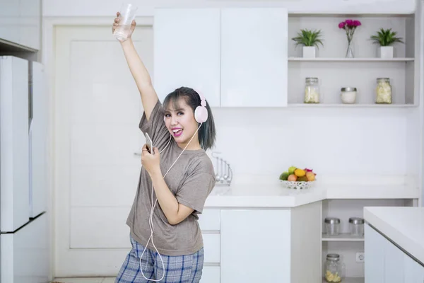 Mulher bonita desfrutando de música na cozinha — Fotografia de Stock