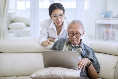 Kızı ile bir dizüstü bilgisayar kullanarak yaşlı adam