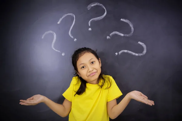 Confused little girl standing with question marks — Stock Photo, Image