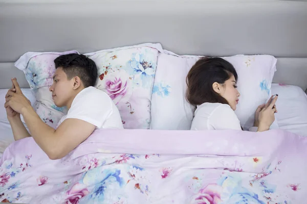 ベッドの上でお互いに背中合いに横たわっているカップル — ストック写真