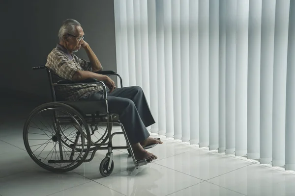 Uomo anziano disabile sembra triste vicino alla finestra — Foto Stock