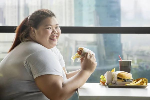 Mujer gorda feliz come una hamburguesa en el restaurante — Foto de Stock