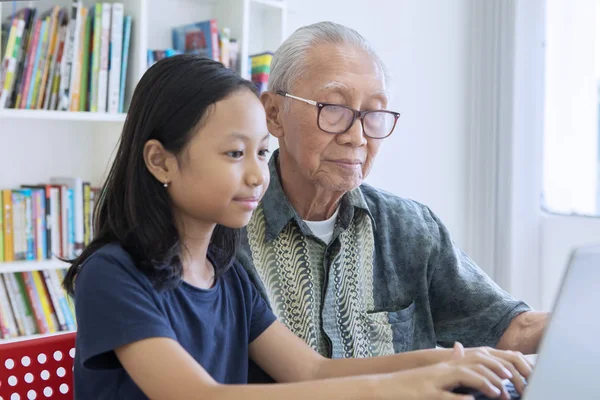Dedesi ile bir dizüstü bilgisayar kullanarak küçük kız — Stok fotoğraf