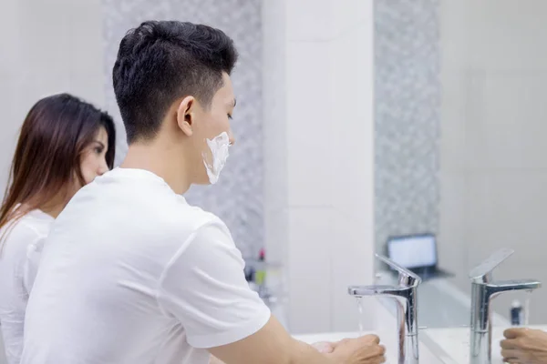 Ο άνθρωπος καθαρίζει το ξυράφι του στο μπάνιο με τη γυναίκα του — Φωτογραφία Αρχείου