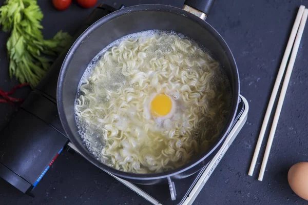 Fideos hervidos con un huevo en una sartén —  Fotos de Stock