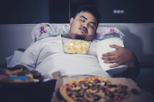 Uomo obeso dormire con cibi spazzatura sul letto — Foto Stock